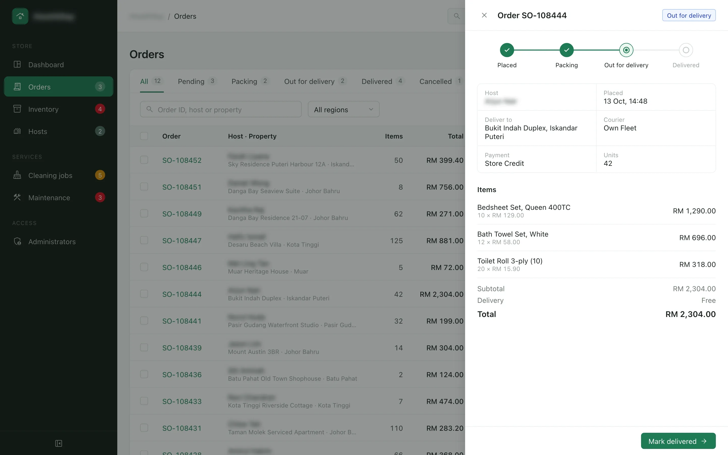 Admin orders list with the drawer for a RM 2,304.00 order of bedsheets, towels and toilet rolls, out for delivery with the company’s own fleet and paid with store credit